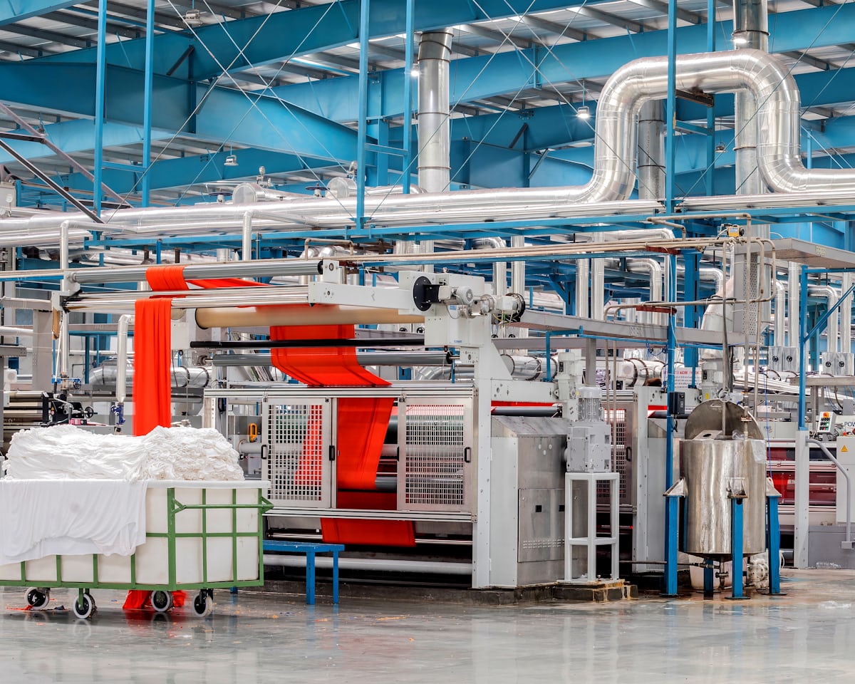 A textile production floor lined with machinery and pipework.
